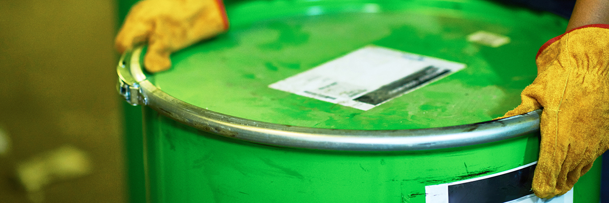 Chemicals being sealed in a green barrel by gloved hands